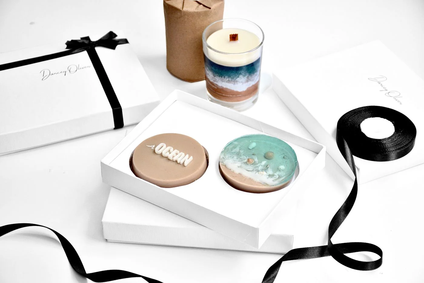 Decorative soaps in a gift box beside a candle.