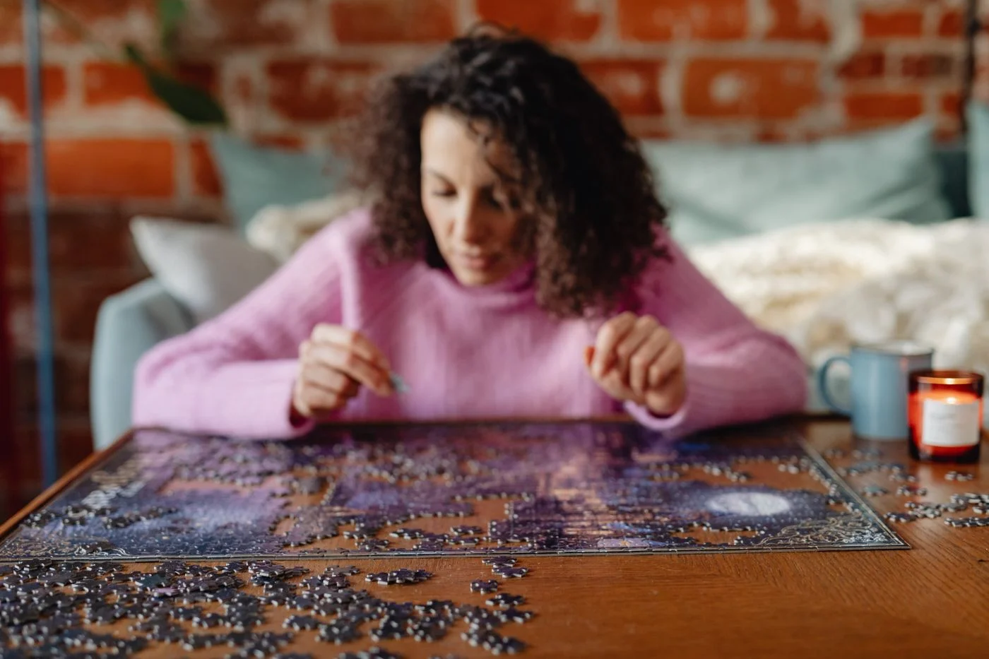 A woman assembling a jigsaw puzzle on a table at home.