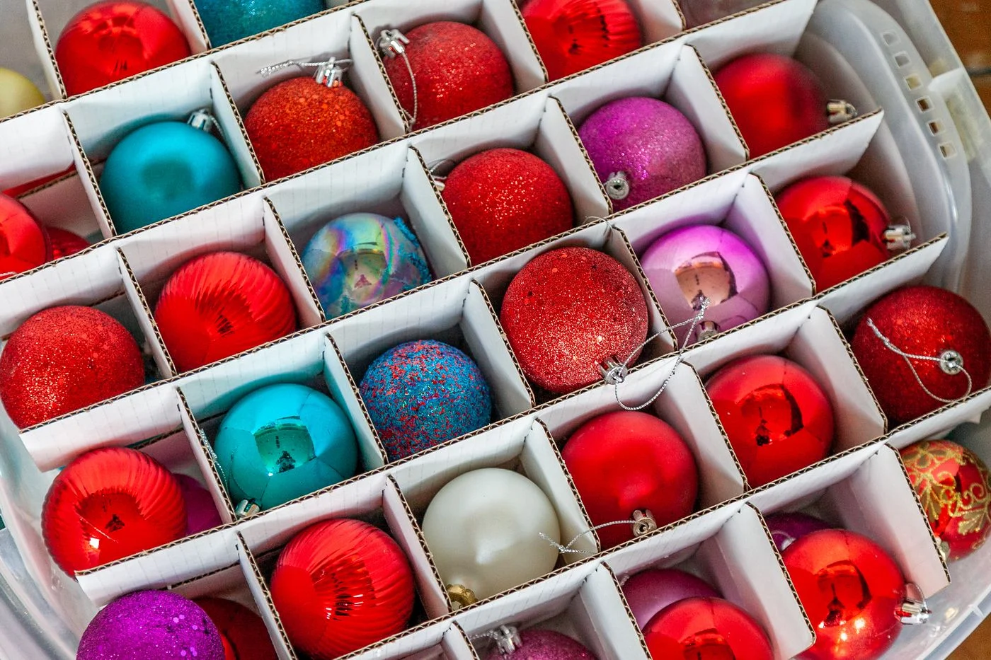 Colorful Christmas baubles arranged in a storage box.