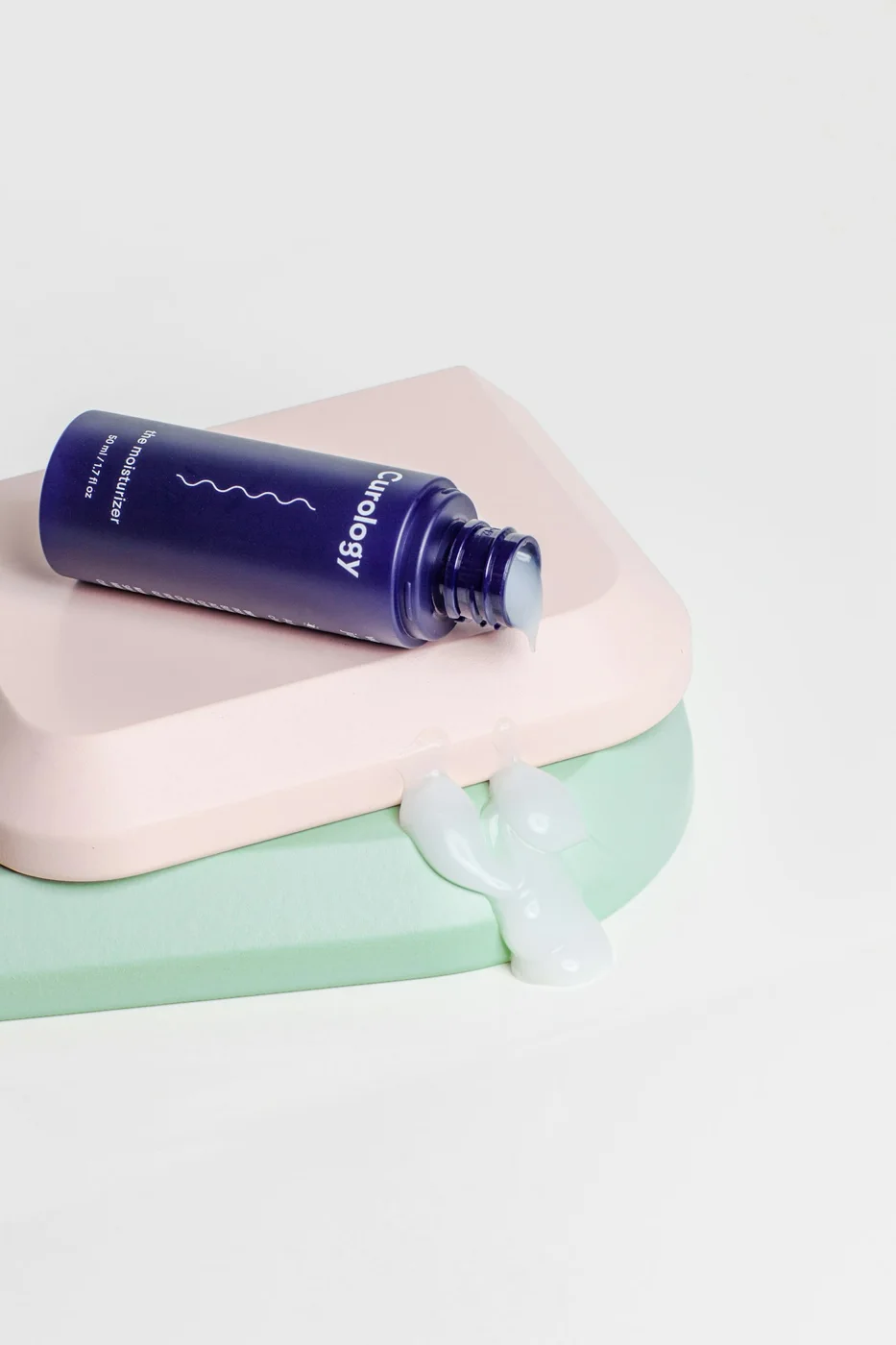 Small cosmetic tubes and containers on pastel surfaces.