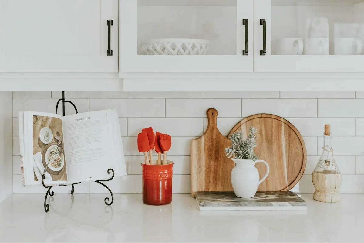 Kitchen utensils, boards, and a hanging towel beside a counter.