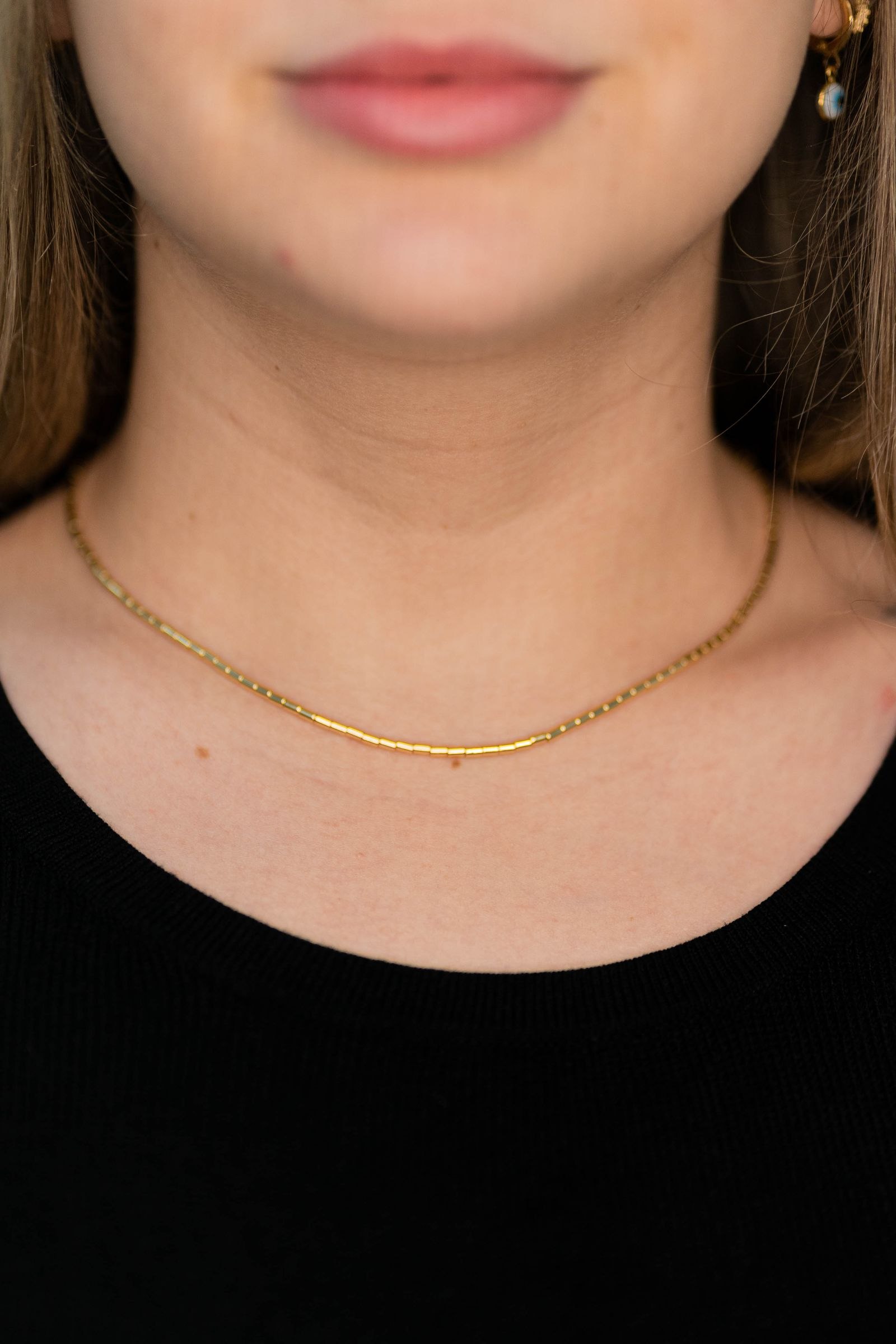 A delicate gold-colored necklace worn with a black top.