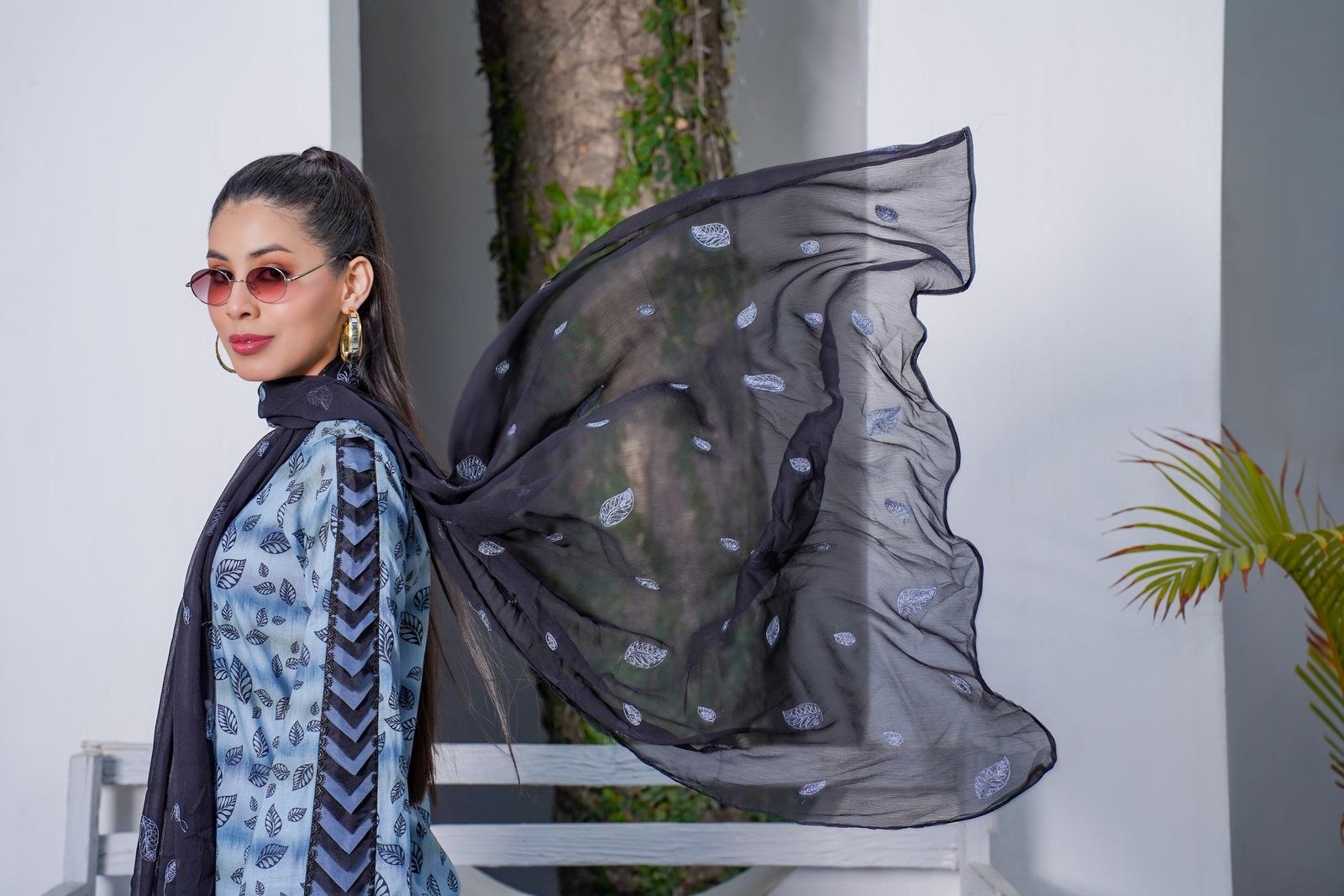 A woman wearing a flowing dark scarf outdoors.