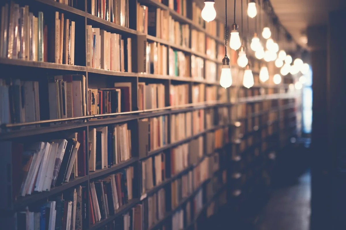 Books on shelves in a warmly lit library.