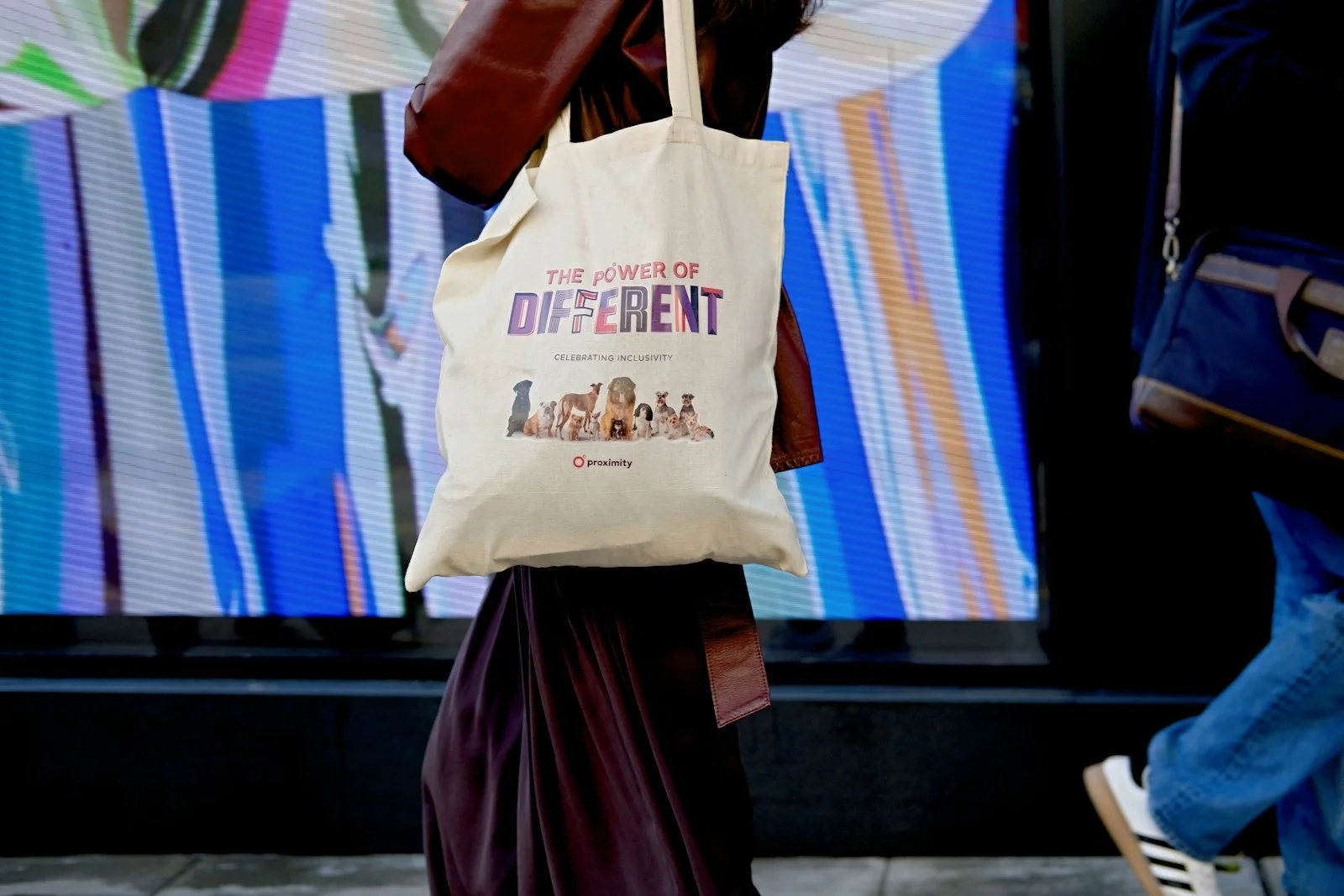 A person carrying a light-colored tote bag outdoors.