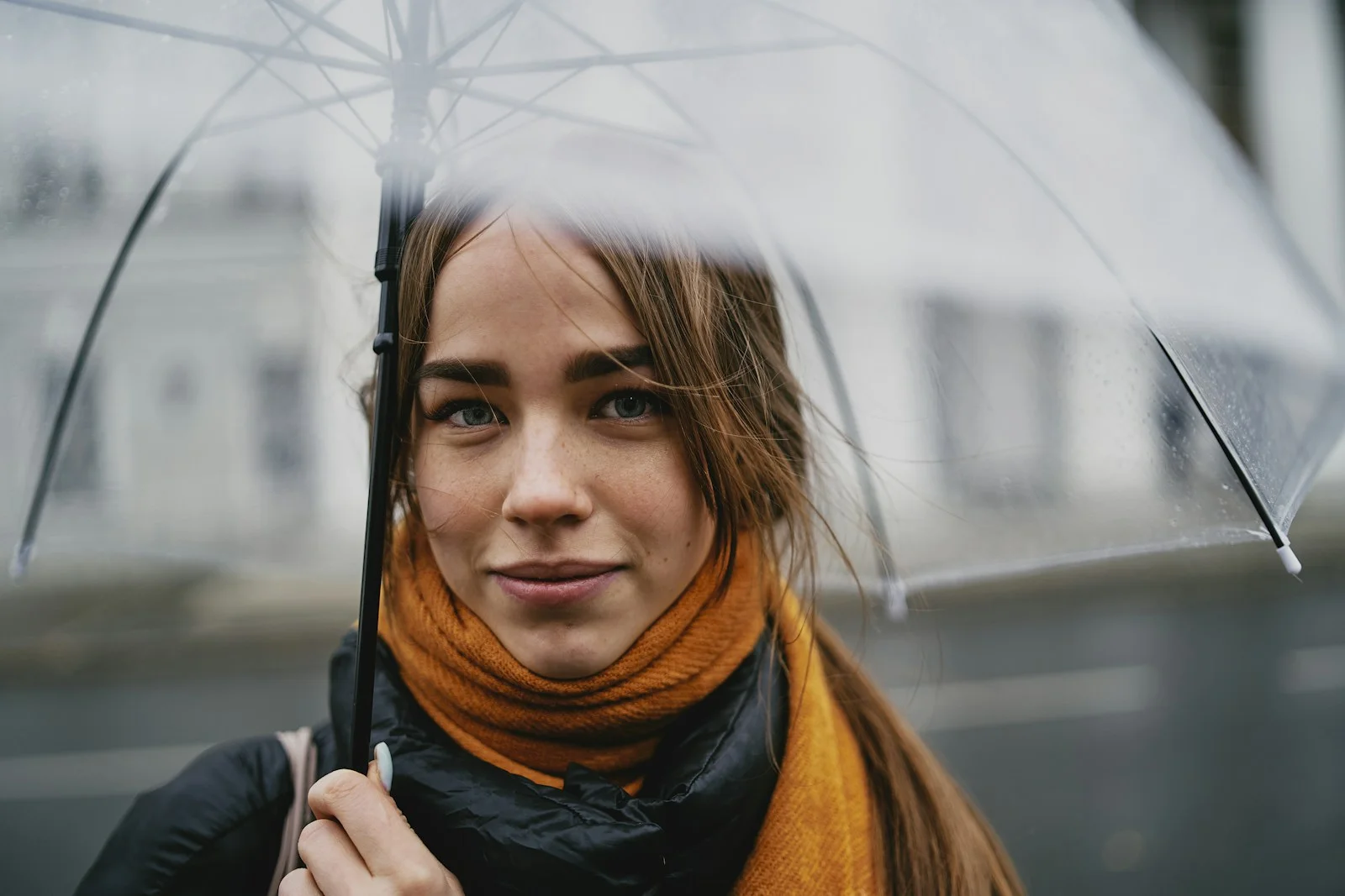 A woman holding a transparent umbrella outdoors.