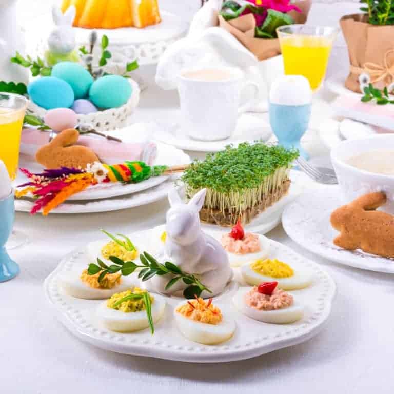 Easter Brunch table set with Easter decorations like a white bunny, deviled eggs, blue dyed Easter eggs.