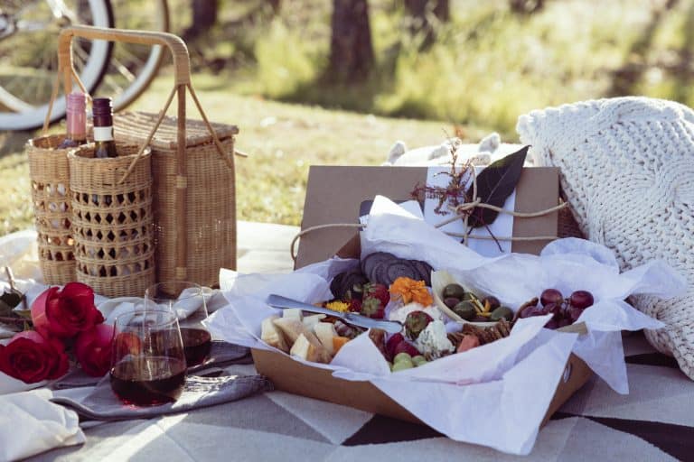 Romantic picnic set up with mixed food platter and wine at sunset
