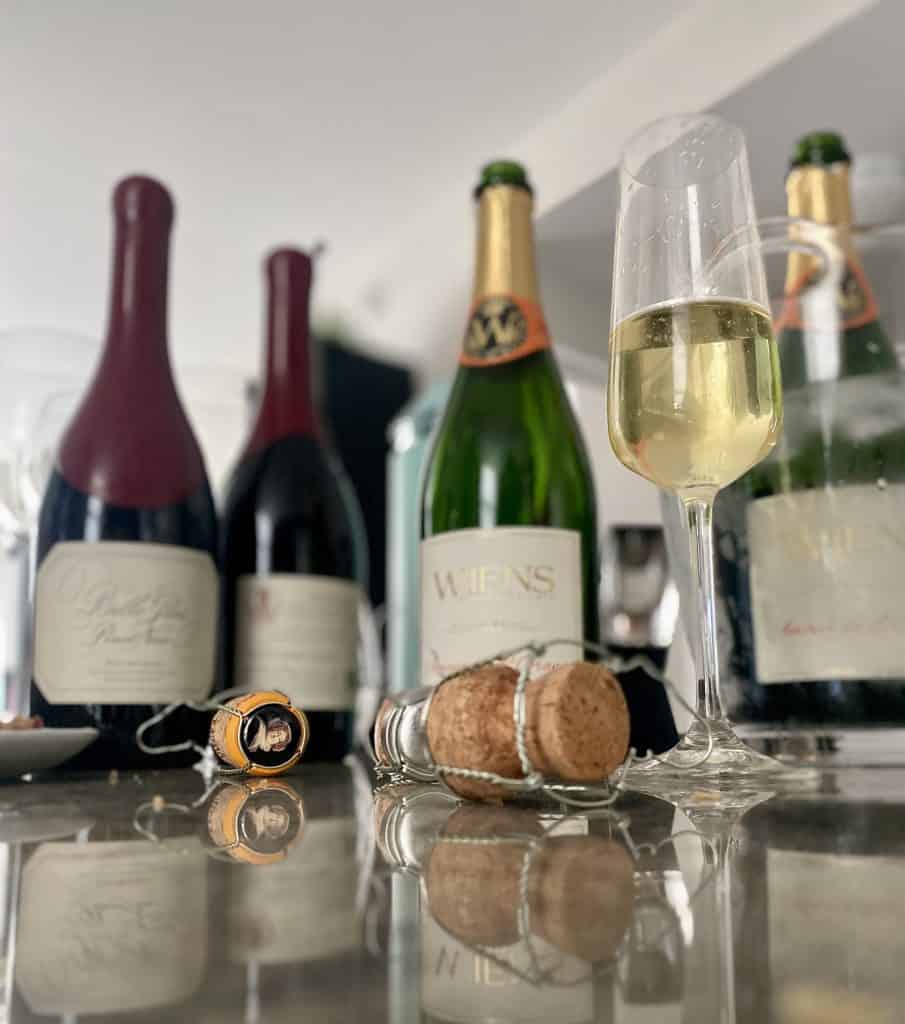 Bottles of wine and champagne on a granite counter with cork popped and glasses half full.