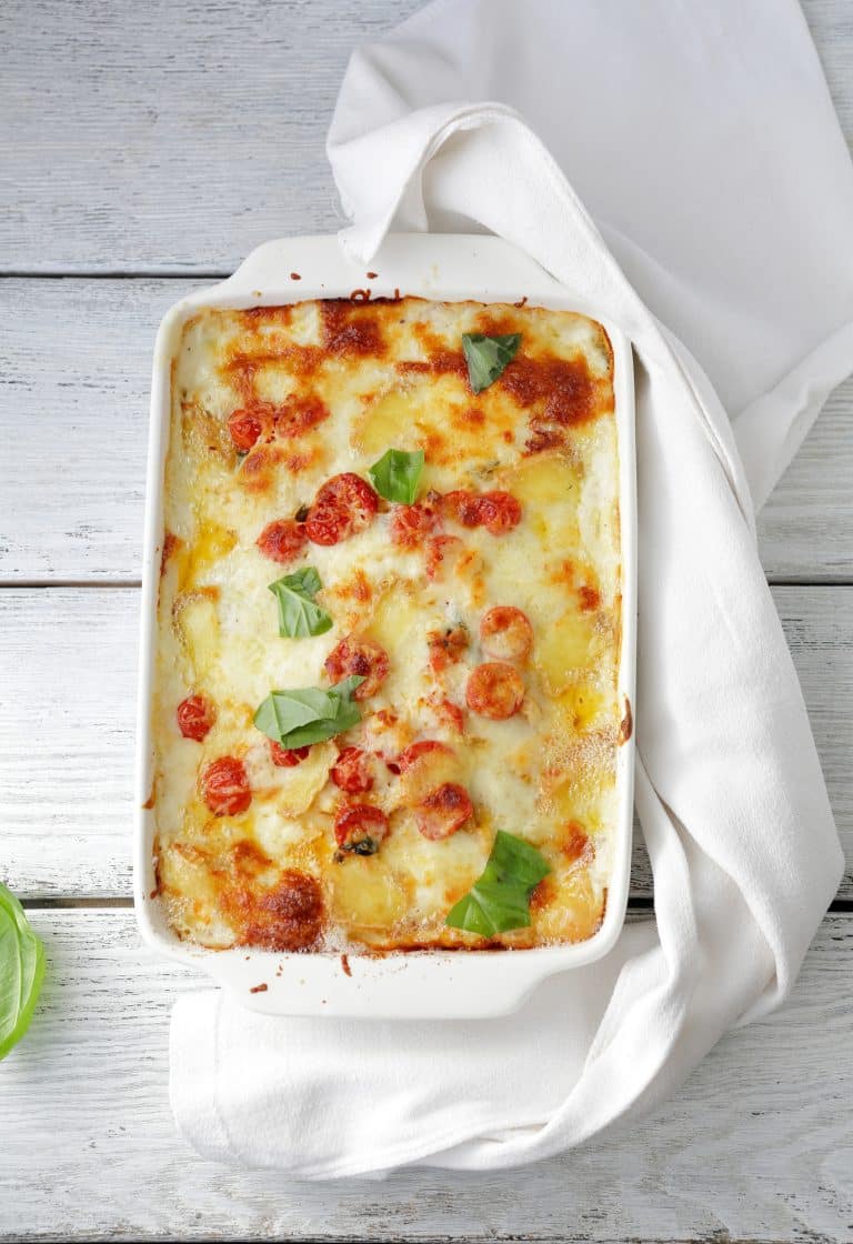 lasagna in white baking dish on white wooden