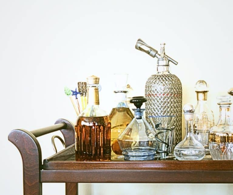 Home mocktail bar. Several bar items set up on a bar cart ready for a party. Different glass containers.