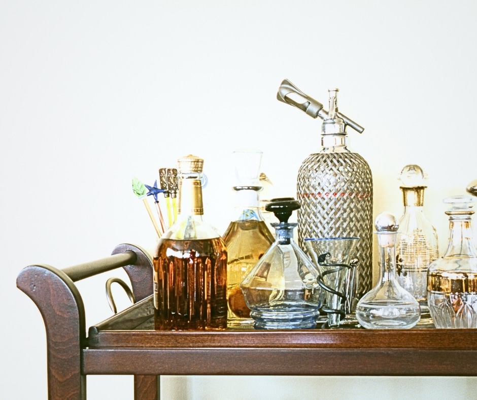 Home mocktail bar. Several bar items set up on a bar cart ready for a party. Different glass containers.