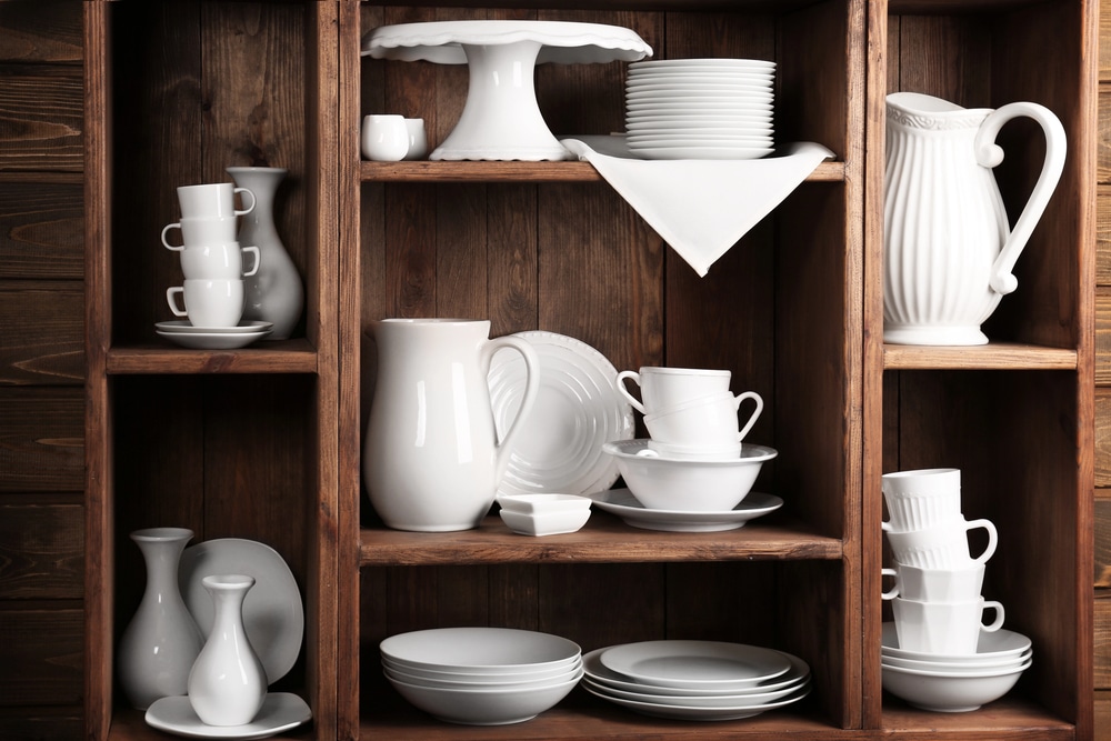 Capsule closet for entertaining. A dark wood cabinet with white entertaining dishes like a cake stand, tea